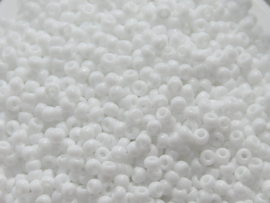 Opaque white seed beads, 3mm in size and round in shape. The image is a close-up of a bowl of full of seed beads so that the beads fill the entire image