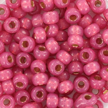 Pink seed beads silverlined, 4mm in size and round in shape. The image is a close-up of a bowl of full of seed beads so that the beads fill the entire image