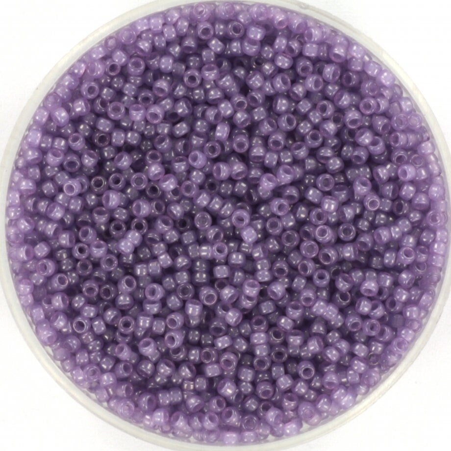 Translucent purple seed beads, 1.5mm in size and round in shape. The image shows a round bowl full of seed beads on a white background