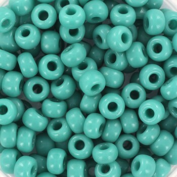 Opaque turquoise green seed beads, 4mm in size and round in shape. The image is a close-up of a bowl of full of seed beads so that the beads fill the entire image