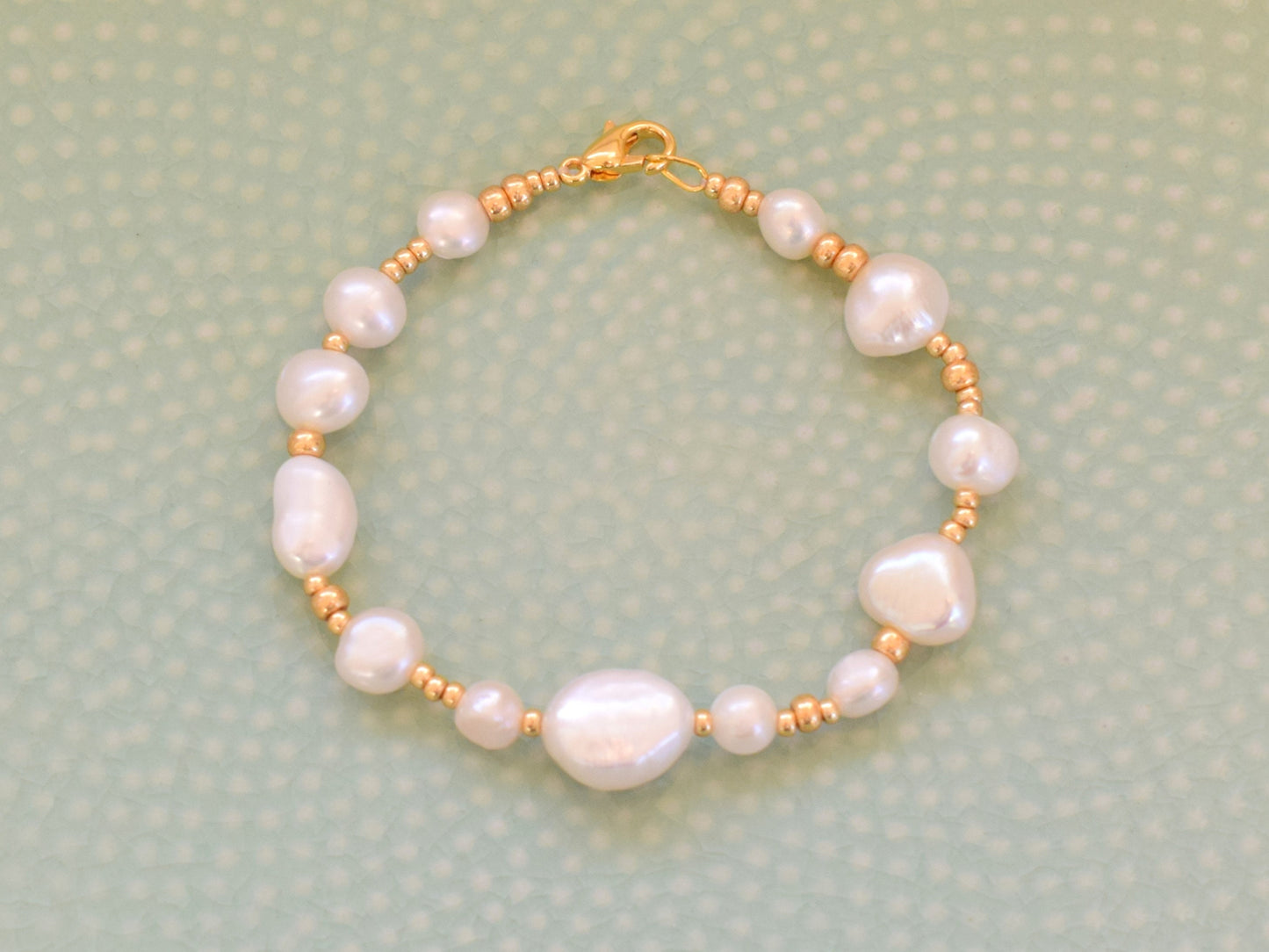 Beaded bracelet with gold seed beads and freshwater pearls in different shapes and sizes.