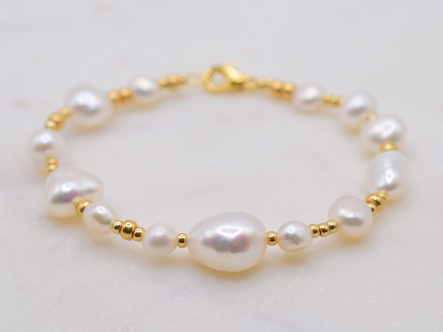 Beaded bracelet with gold seed beads and freshwater pearls in different shapes and sizes.