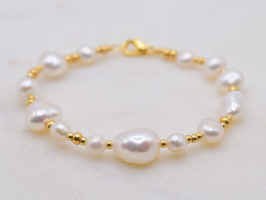 Beaded bracelet with gold seed beads and freshwater pearls in different shapes and sizes.